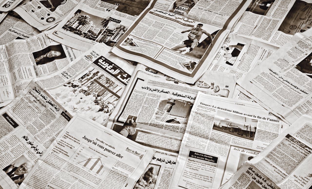 services-02 A collection of Arabic newspapers spread across a surface, showcasing diverse headlines and articles.