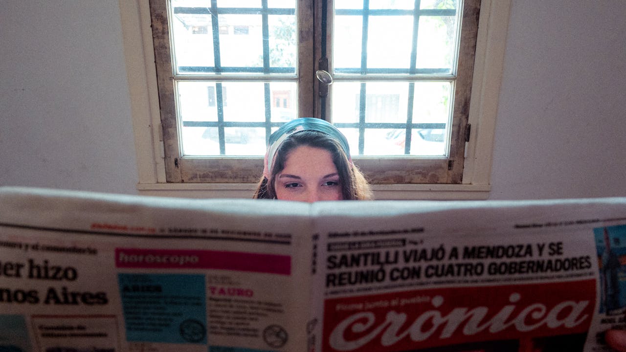 services-01 A woman reads a vintage newspaper by a window, creating a nostalgic interior scene.