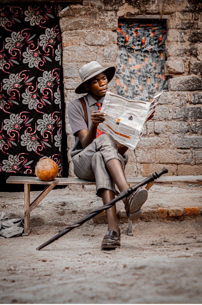 Outdoor portrait of a young man reading a newspaper, exuding vintage charm in Southern Malawi.